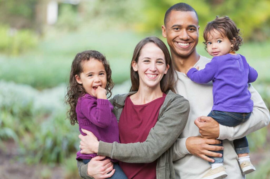 Mom and dad smile while holding their 2 kids before the dentist in San Antonio, TX