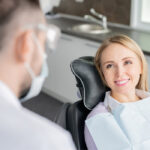 Blonde woman smiles while sitting in the dental chair before root canal therapy to save your infected tooth