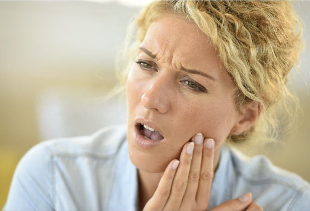 woman holds her jaw in pain with TMD
