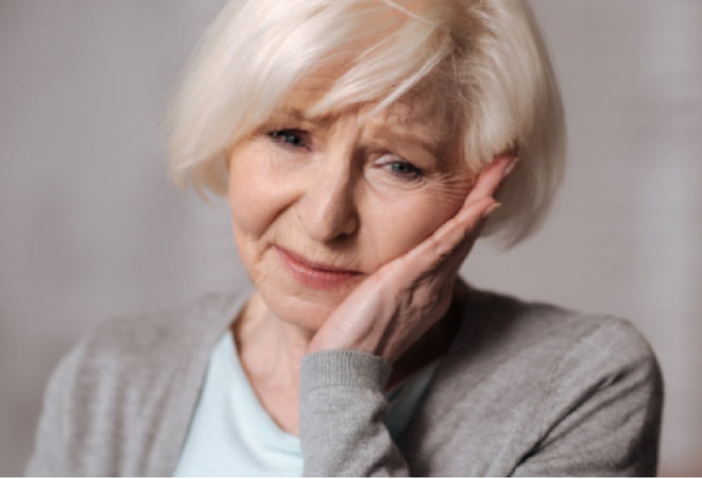 senior woman holds her jaw in pain with a missing tooth