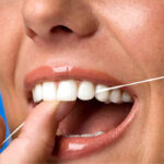 close up of a woman flossing her teeth