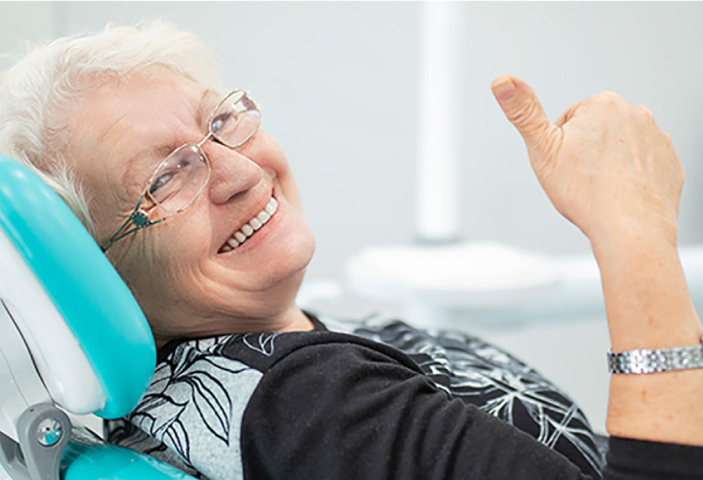 senior woman in the dental chair gives a thumbs up for a good local dentist