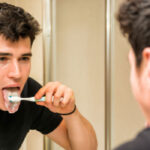 young man brushes his tongue to prevent bad breath