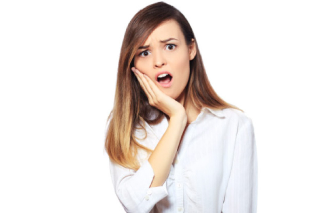 young woman holds her jaw in pain with a toothache