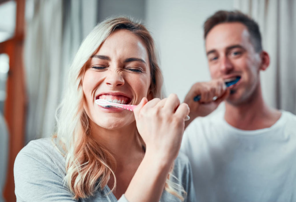 young couple brushing their teeth together with fluoride toothpaste