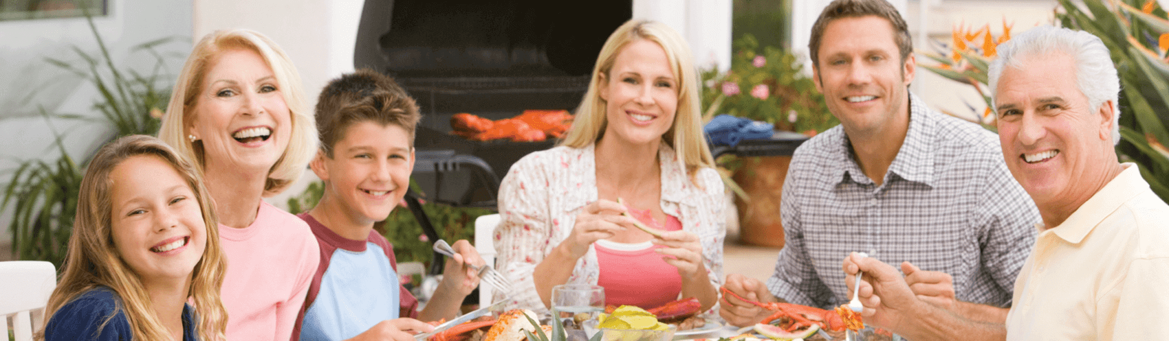 Family of six smiling together outside during a meal