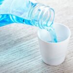 mouthwash being poured into a small cup to fight bad breath