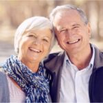 senior couple hug and smile showing off their white teeth