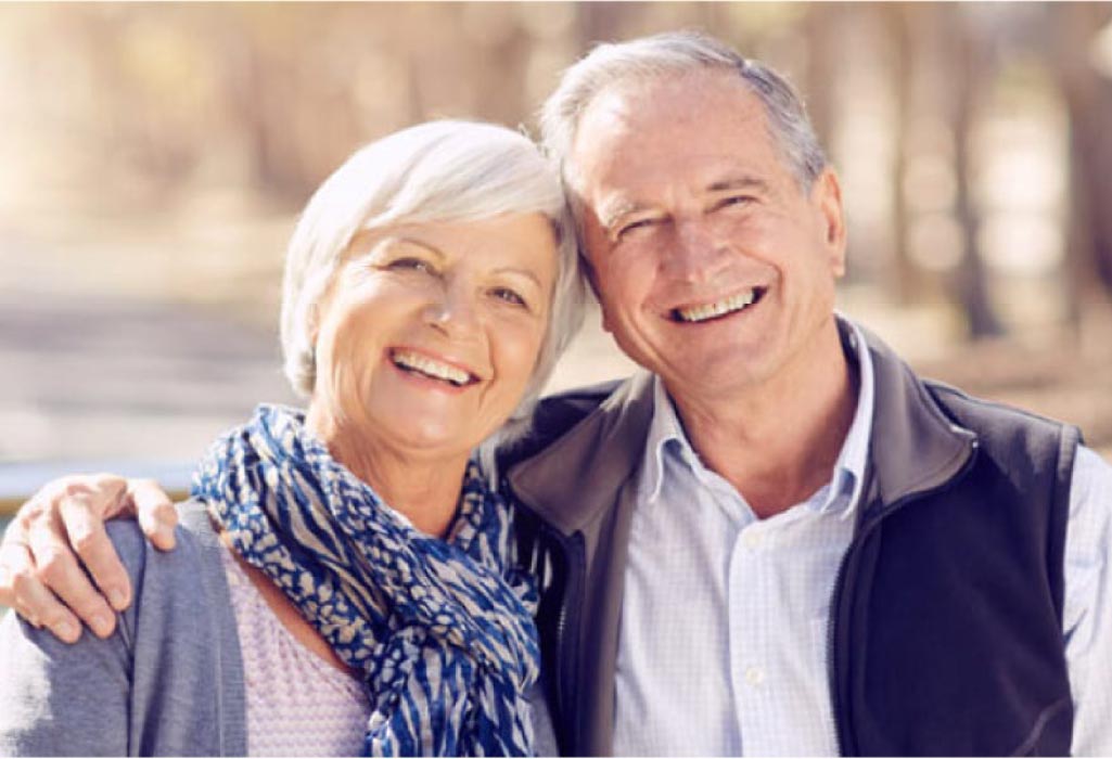 senior couple hug and smile showing off their white teeth