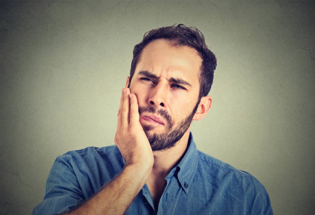 bearded man holds his jaw with gum pain