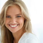 young blond woman flashes a bright white smile