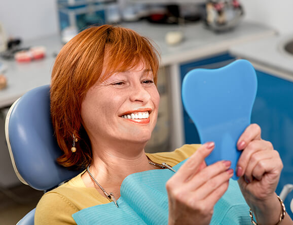 woman examining her smile in a mirror