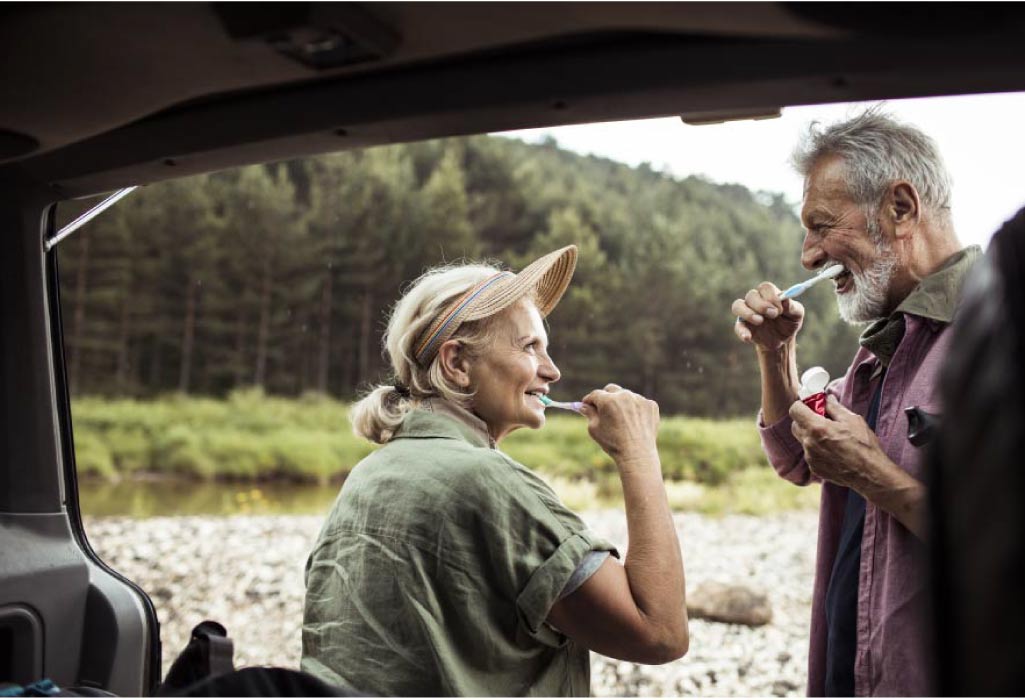 senior couple brush their teeth together while camping