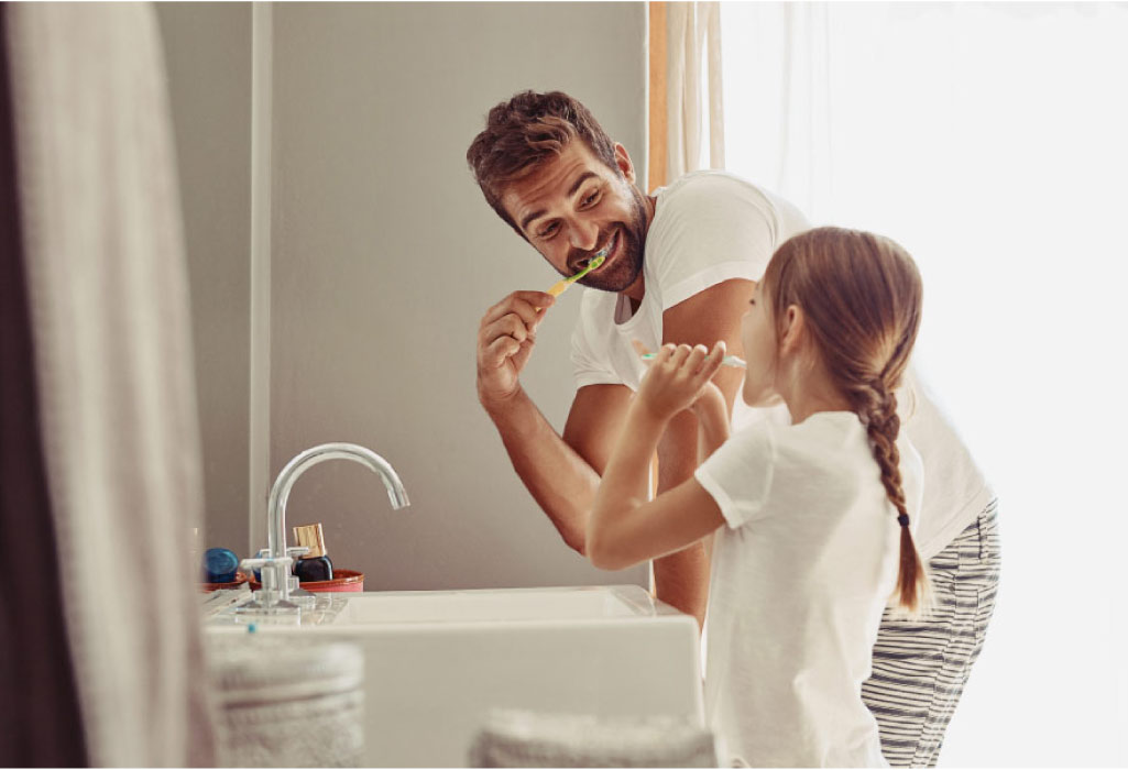 father and young daughter brush their teeth together