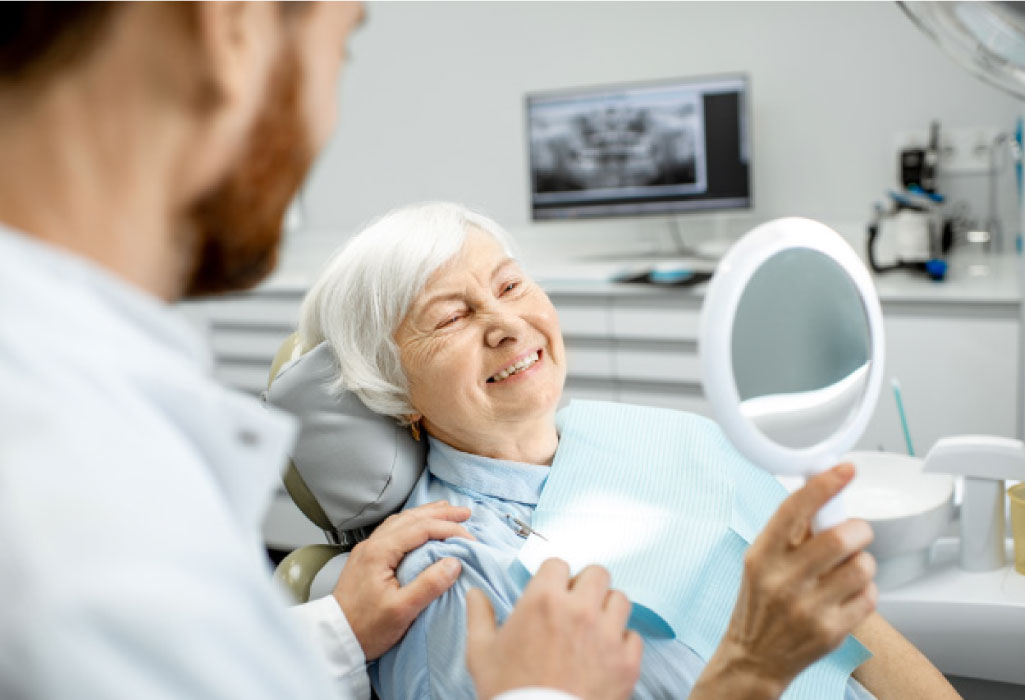 senior woman in the dentist chair looking in a mirror at her teeth