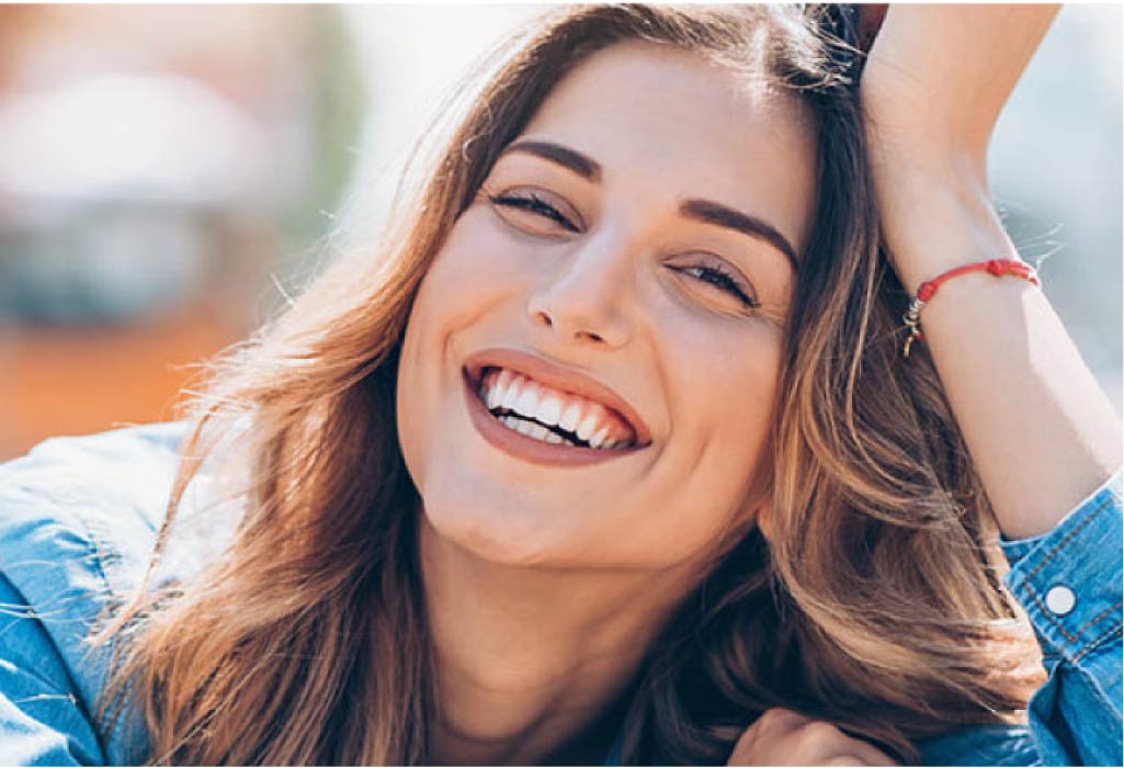 young woman smiles after getting a dental crown