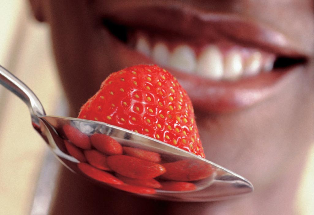 closeup of a person about to eat a strawberry in a spoon