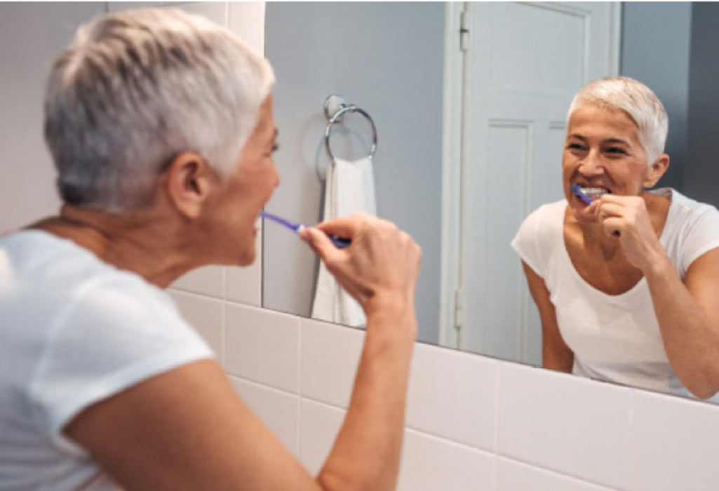 senior woman brushes her teeth to prevent a root canal