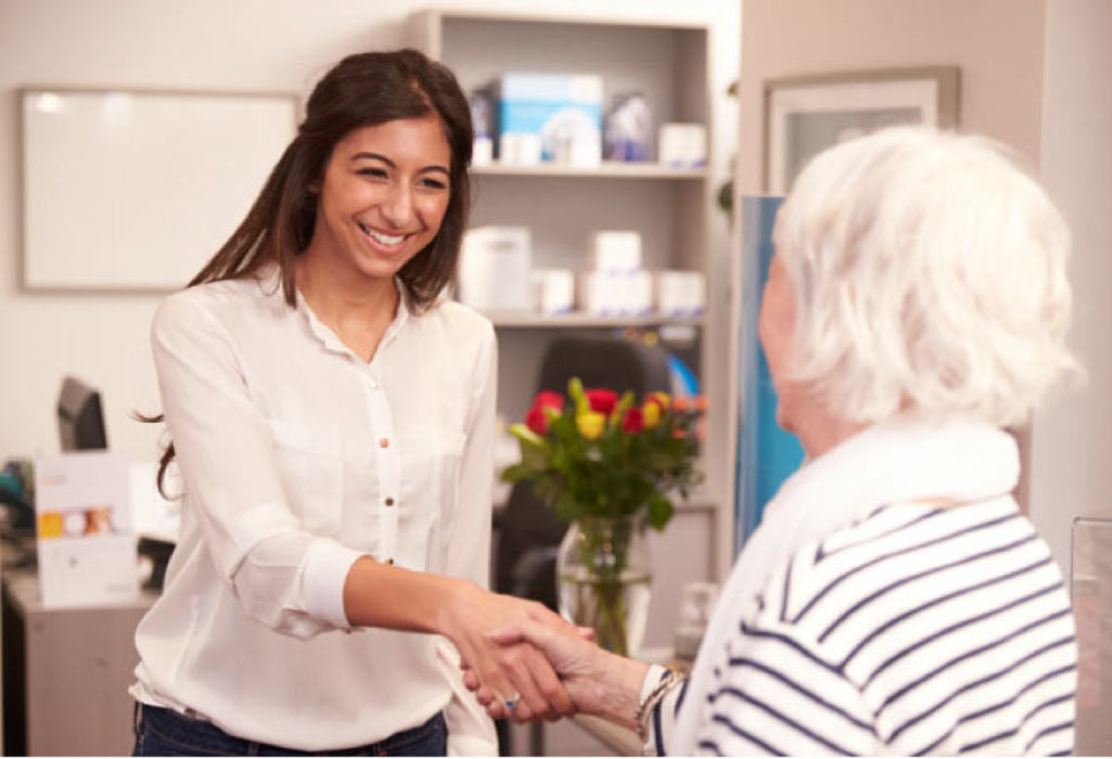 senior woman is greeted by a young woman at a new dentist office