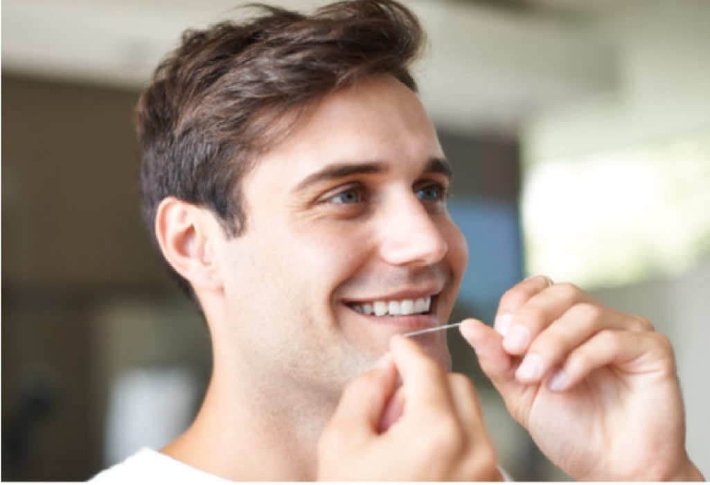 man smiles while flossing his teeth