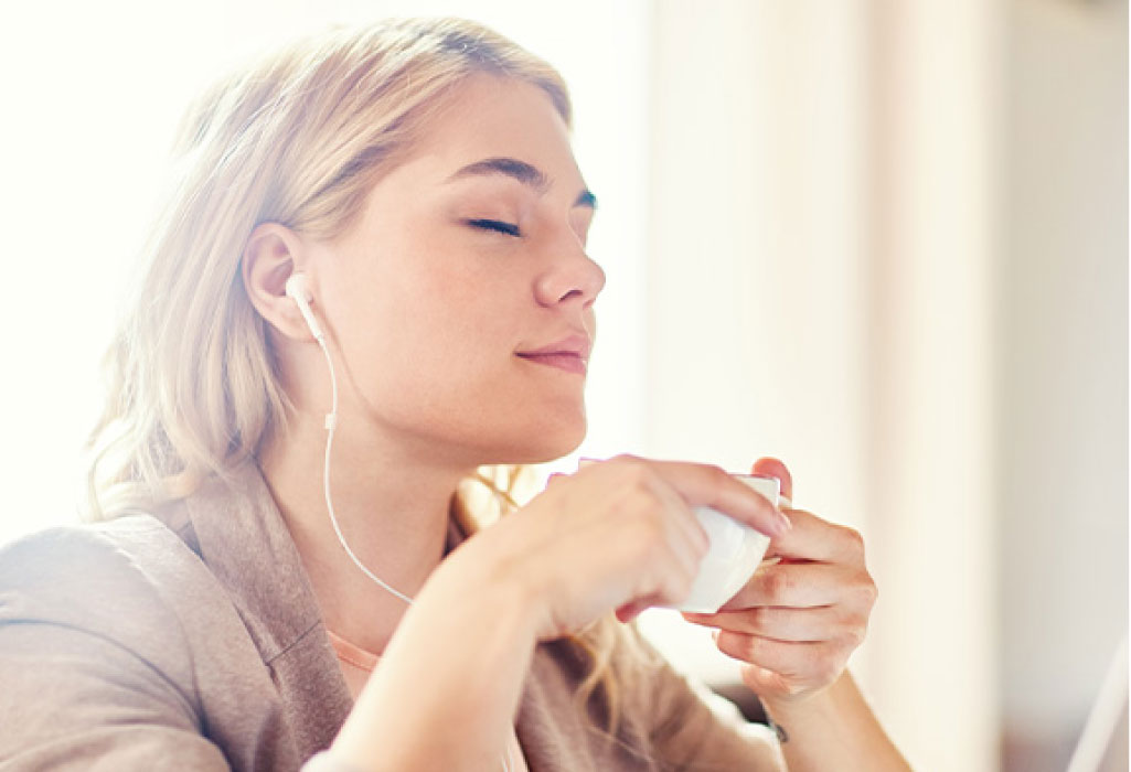 woman relaxes at the the dentist office with headphones and a cup of tea