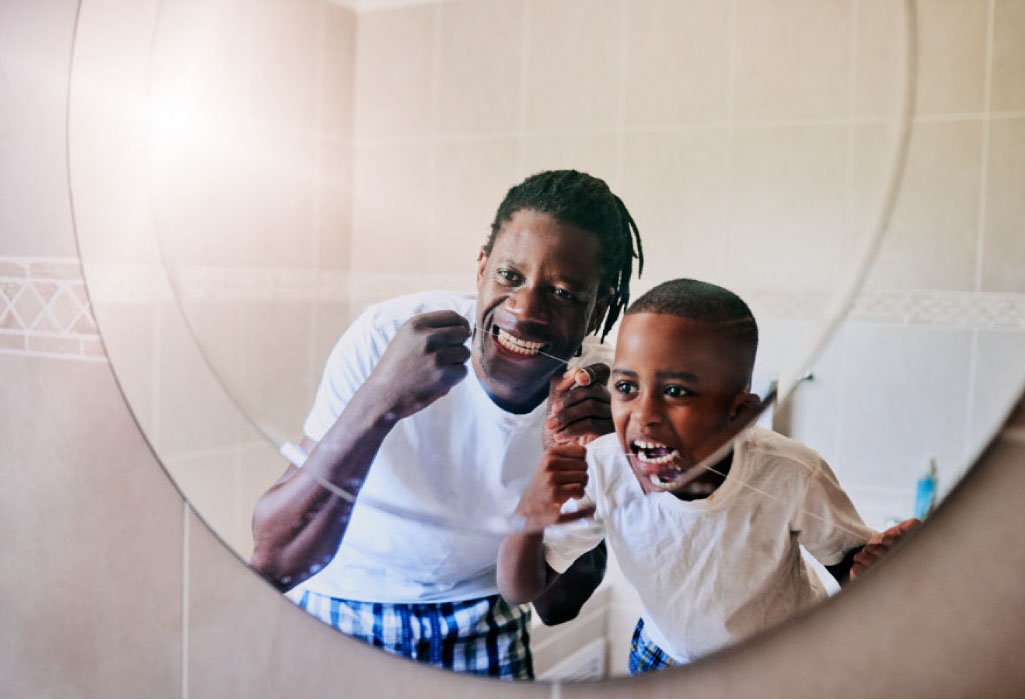 father and young son floss their teeth together