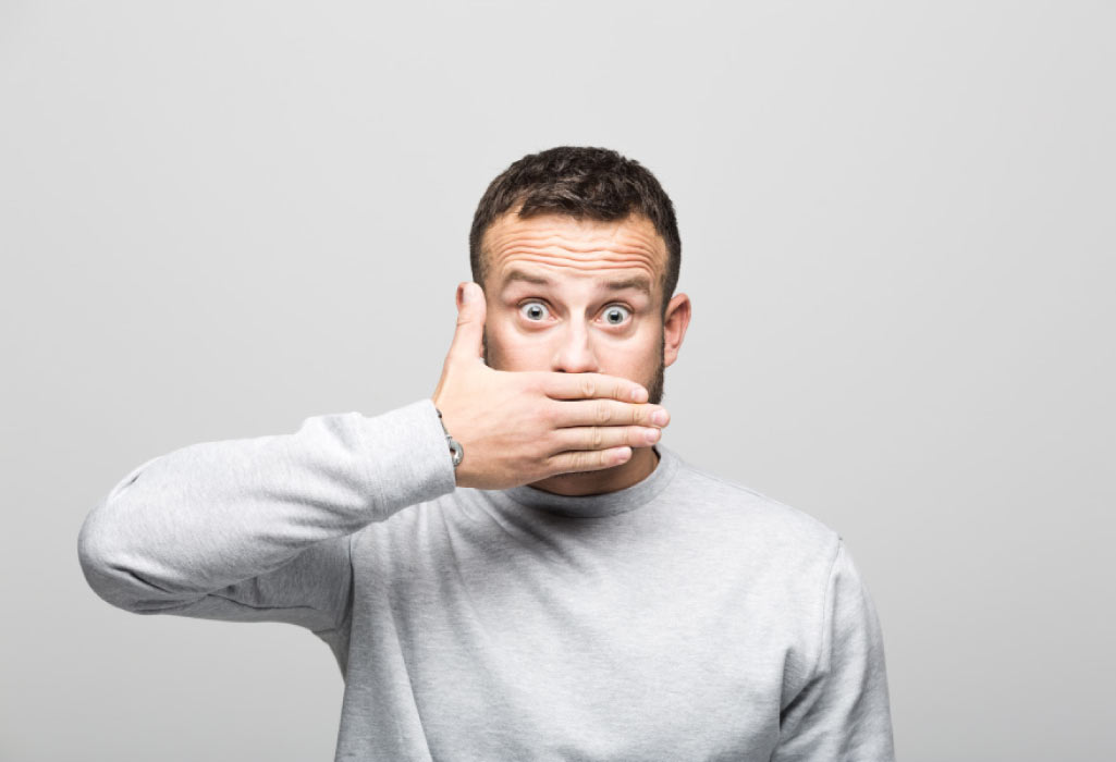 surprised man covers his mouth with his hand to hide bad breath