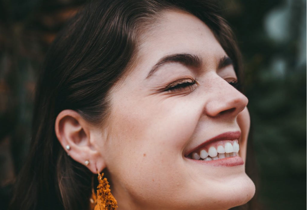 woman smiles showing off her dental veneers