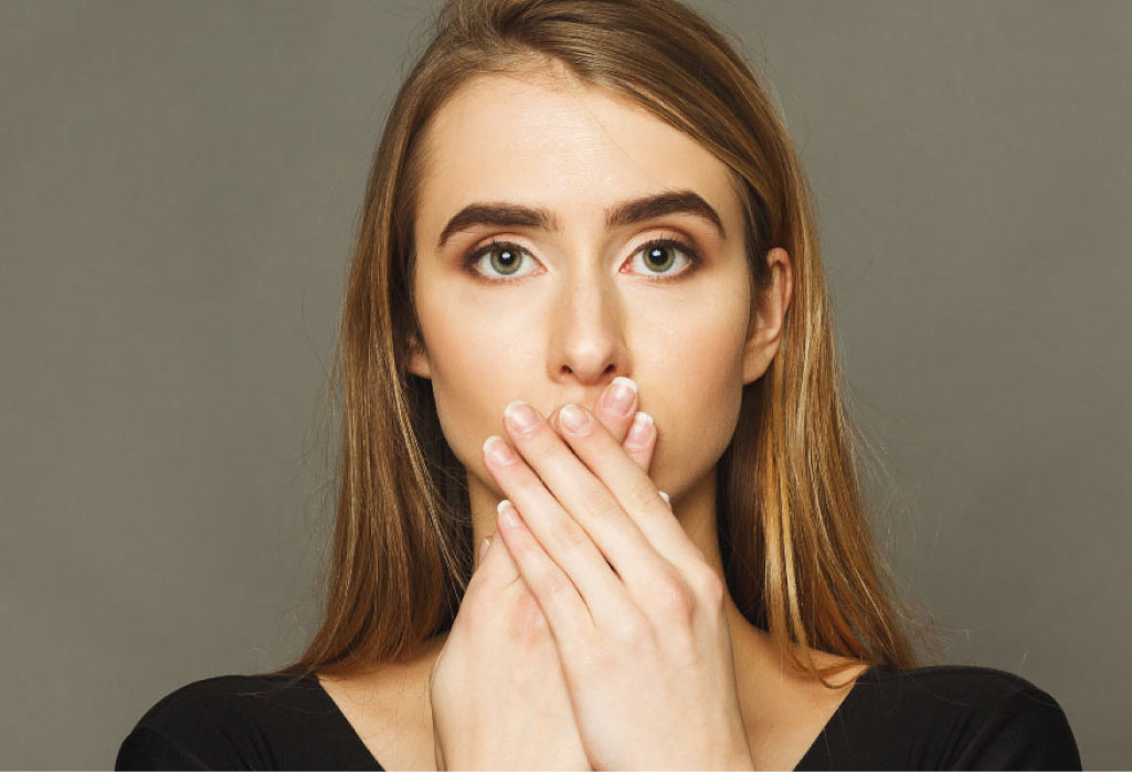 young woman covers her mouth with her hands to hide receding gums