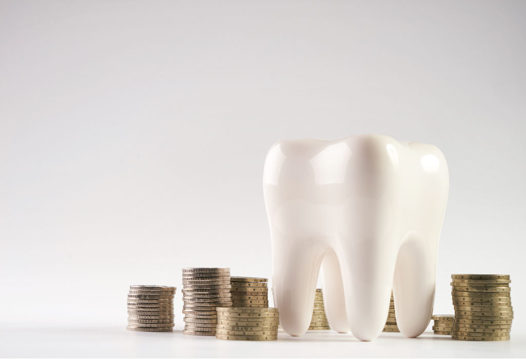 tooth next to stacks of coins