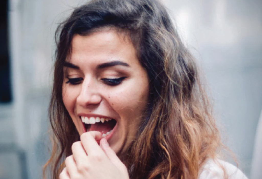 woman holds her tooth because of a broken dental veneer