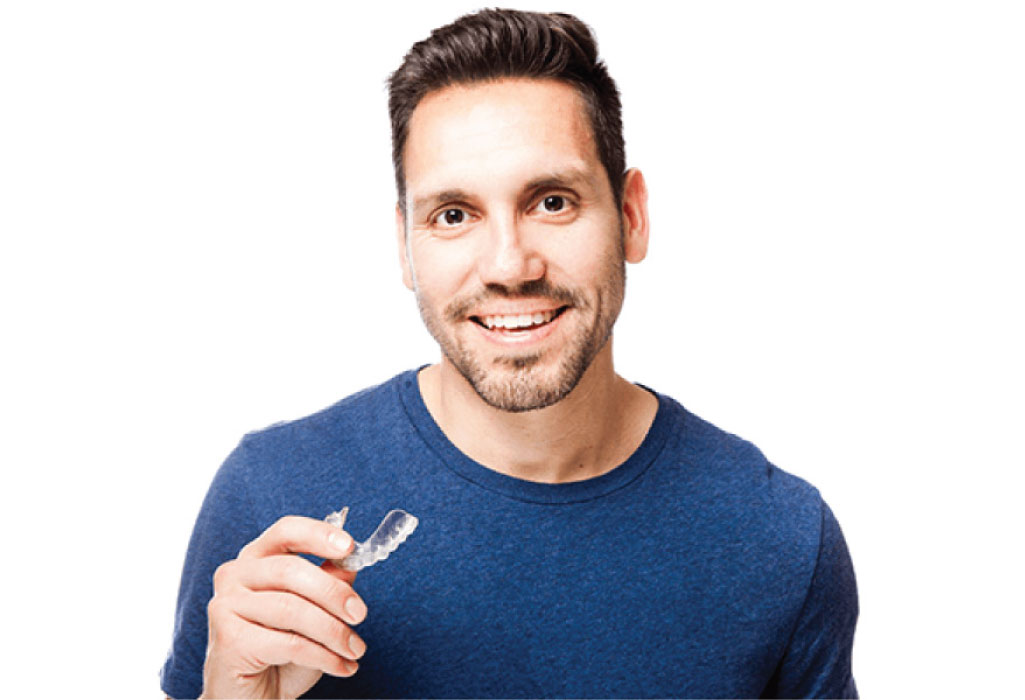 man holds his clear aligner and smiles after finding out about bruxism relief